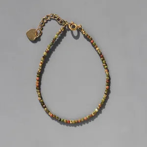 Détail macro du bracelet en perles de pierre naturelle avec breloque cœur dorée