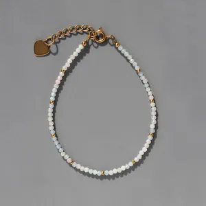 Détail d'un bracelet en perles colorées avec breloque cœur et fermoir mousqueton doré