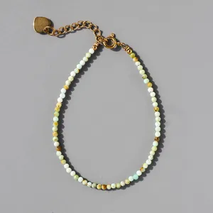 Detail of natural stone beaded bracelet with 18k gold heart charm and extension chain