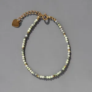 Détail de perles en pierre naturelle facettées avec perles d'espacement dorées et breloque cœur