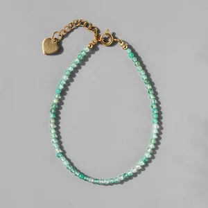 Detailed shot of turquoise beaded bracelet with 18k gold heart charm and clasp