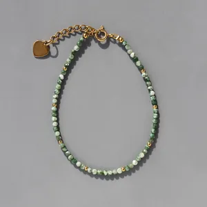 Détail de bracelet bohème en pierre avec pendentif cœur doré et fermoir mousqueton