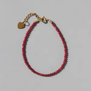 Detailed shot of red faceted beads bracelet with gold heart pendant and lobster clasp