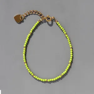 Détail du bracelet en perles facettées vert fluo avec breloque cœur dorée et fermoir