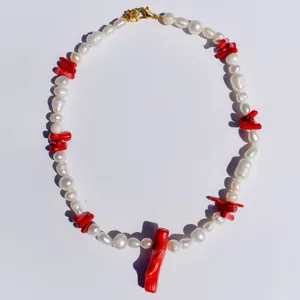 Dettaglio di collana di perle d'acqua dolce naturali con coralli rossi e chiusura dorata