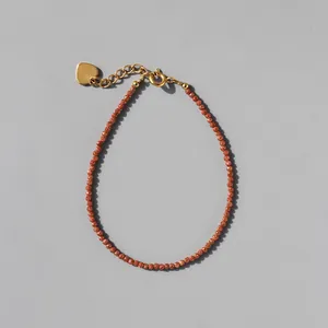 Detail of beaded gemstone bracelet with heart charm and 18k gold plated clasp