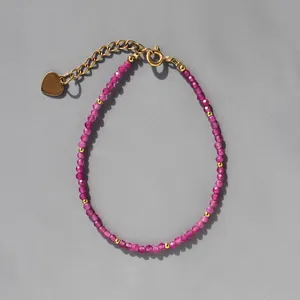 Détail du bracelet en perles roses avec pendentif cœur doré et fermoir mousqueton