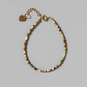 Macro view of dainty multi-color natural stone beaded bracelet with 18k gold heart charm