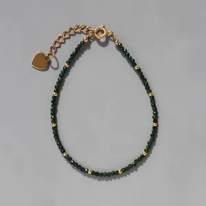 Détail du bracelet en pierres vert foncé avec breloque cœur doré et chaîne d'extension