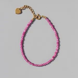 Detail of pink natural stone beaded bracelet with gold heart charm and 18k gold chain