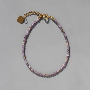 Détail de perles en cristal violet avec accents dorés et pendentif en forme de cœur