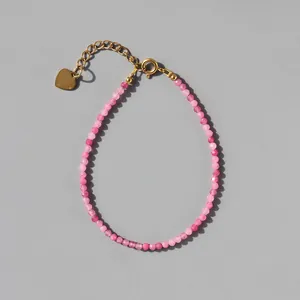 Detail of pink natural stone beaded bracelet with 18k gold plated heart charm and clasp