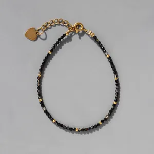 Détail de perles noires facettées et breloque en cœur sur bracelet perlé bohème