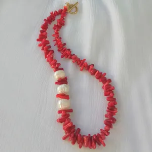 Dettaglio di perle rosse a corallo con tre perle bianche e chiusura a T dorata