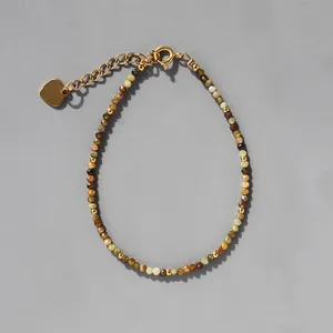 Gros plan du bracelet bohème en pierres naturelles, perles dorées et pendentif coeur