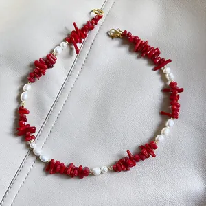 Dettaglio della collana con perle di corallo rosso, perle bianche e chiusura a moschettone dorata