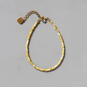 Macro detail of natural stone beaded bracelet with 18k gold plated heart charm and clasp