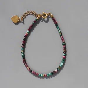 Détail d'un bracelet bohème en pierres naturelles avec pendentif cœur doré et chaîne