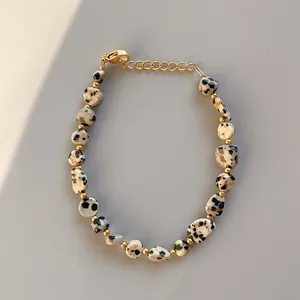 Dettaglio del bracciale di diaspore dalmata con perline dorate e chiusura a moschettone
