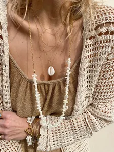 Set di collane bohémien a strati con perle naturali, conchiglie e catene d'oro su modella