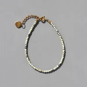 Detailed view of natural stone beaded bracelet with 18k gold heart charm and lobster clasp