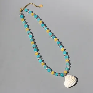 Colorful beaded necklace with a white scallop shell pendant on a grey background