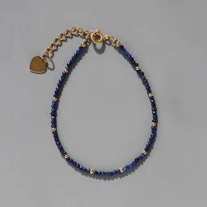 Détail d'un bracelet en perles avec pierres bleues, touches d'or et cœur