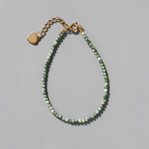 Detail of beaded natural stone bracelet with 18k gold plated heart charm and extension chain