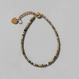 Detail of beaded natural stone bracelet with 18k gold plated heart charm and clasp