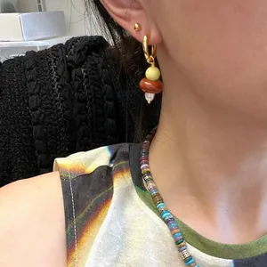 Orecchini a cerchio dorati con perle in pietra naturale colorata e perla a goccia su modella