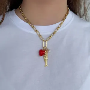 Collier chaîne doré avec cœur rouge, poisson et perle sur t-shirt blanc