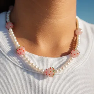 Vue détaillée des perles de fraise en verre et perles d'eau douce sur le collier