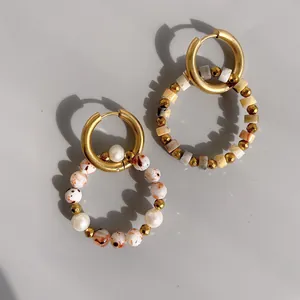 Detail of gold hoop earrings with natural stone beads and pearl charms for boho look