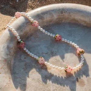 Détail des perles de verre fraise et perles d'eau douce sur un collier de plage
