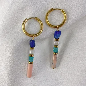 Macro detail of gold hoop earrings with multi-colored natural stones and pearl drop beads