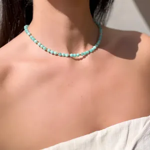 Collana bohémien con perline turchesi e distanziali dorati indossata al sole