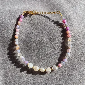 Dettaglio di perle di agata naturale e perle barocche su un bracciale dorato