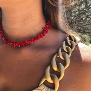 Dettaglio ravvicinato di una collana in corallo rosso a forma di ramo sul collo di una donna