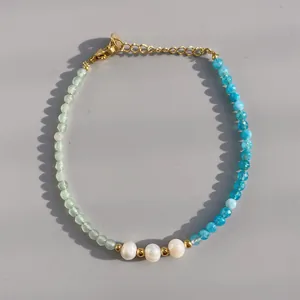 Dettaglio del bracciale con pietre naturali verdi e blu e perle bianche su catena dorata