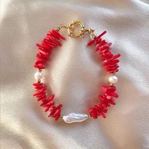 Dettaglio di perline di corallo rosso e perla barocca su collana con chiusura oro