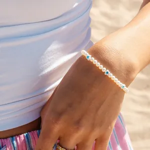 Détail du bracelet en perles de fraise en verre et perles d'eau douce au poignet