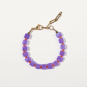 Détail du bracelet en perles violettes avec accents orange et chaîne trombone dorée