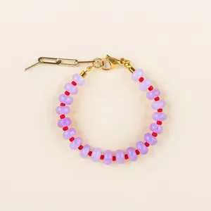 Détail du bracelet perlé avec pierres violettes, séparateurs rouges et fermoir doré