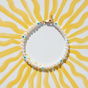 Détail du bracelet en perles d'eau douce avec fleurs œil bleu et fermoir doré