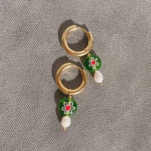 Detail of gold hoop earrings with green floral glass beads and white baroque pearls