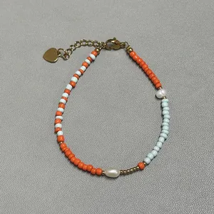 Macro shot of colorful glass beads with freshwater pearls and gold heart charm on bracelet