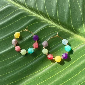 Colorful natural stone beaded hoop earrings on a tropical green leaf in sunlight