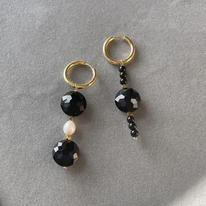 Detailed close-up of handmade asymmetrical beaded earrings with natural black stones