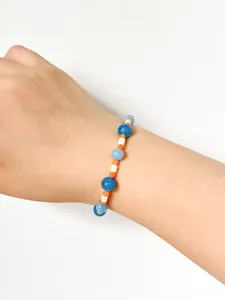 Close-up of blue and orange stone beaded bracelet with white shell spacers on wrist