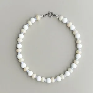 Dettaglio della collana con perle in pietre naturali bianche, beige e blu con chiusura